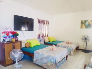 Two single beds with floral-patterned bedding, a flat-screen TV, and a vase of flowers adorn this cozy space.