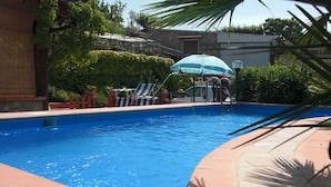 En swimmingpool med liggestole og et overdækket område.