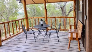 A wooden deck with a table and chairs, a bench, and a view of trees. - Cabin at Sunset Ranch with Sunset Resort on Medina Lake access! (Mico)