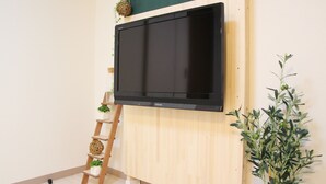A flat-screen TV mounted on a wooden wall, a wooden ladder, and a potted plant. - The Neighbors Tsukamoto (Osaka)