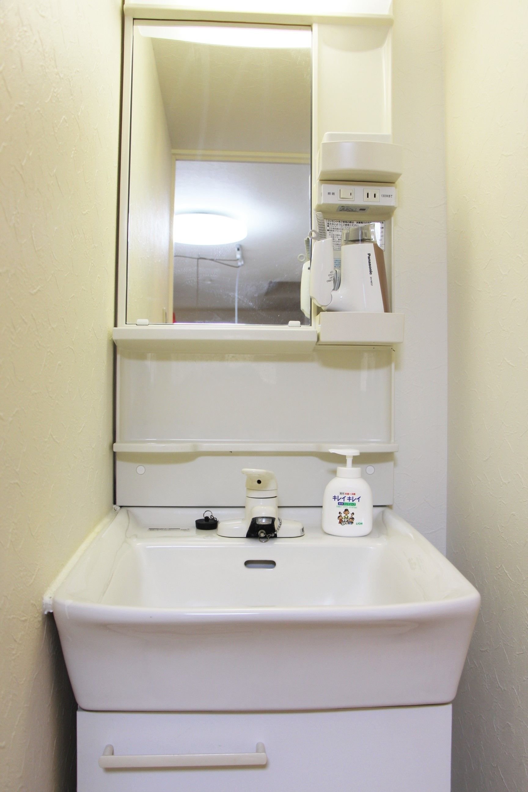 A bathroom with a white sink, mirror, and a coffee maker on the countertop.