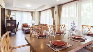 Un comedor con una mesa de madera dispuesta para cuatro personas, rodeada de sillas de mimbre.