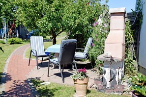 Eine Terrasse im Freien mit einem Ziegelweg, einem Tisch mit Stühlen und einer Steinstruktur.