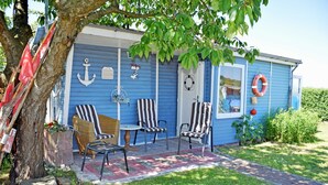 Un bâtiment bleu avec des chaises à rayures et une table à l’extérieur.