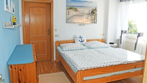 Une chambre avec un lit en bois, un mur bleu, une porte en bois, une étagère avec une figurine et un tableau sur le thème de la plage.