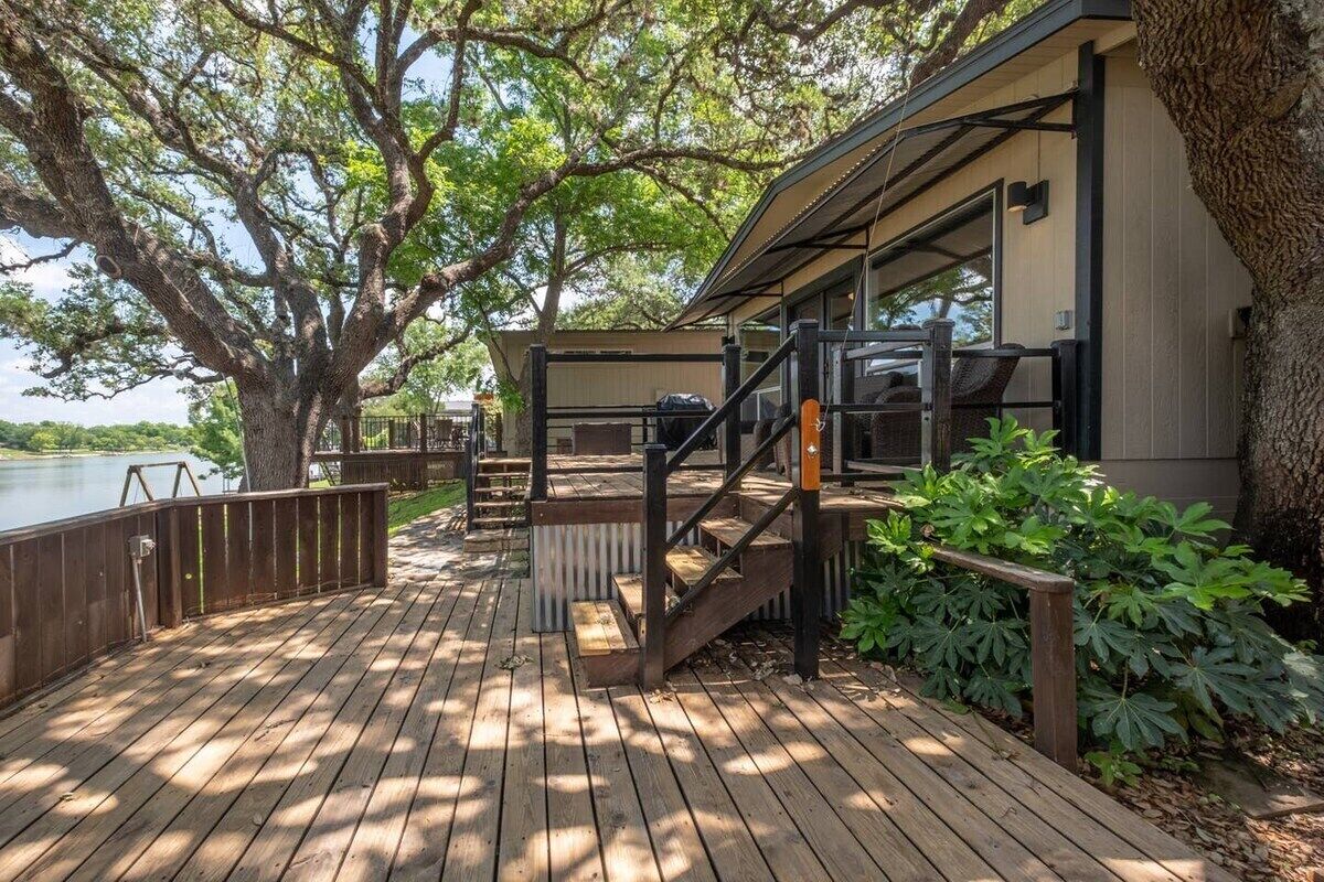 A wooden deck with a covered seating area, a staircase, and a view of a lake.
