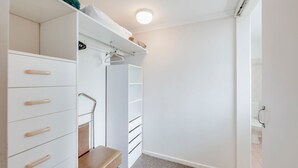 A walk-in closet with white storage units, a bench, and a hanging rack. - Horizons 3-16 Miller Bargara (BARGARA)