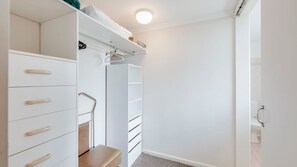 Un vestidor con estanterías blancas, una banca y una barra para colgar ropa.