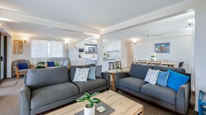 Una sala moderna con dos sofás grises, una mesita de centro y un comedor con una mesa y sillas de madera.