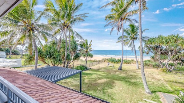 Un balcón con vista a una playa y palmeras.