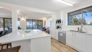 Una cocina moderna con una isla central, lavavajillas y vistas a palmeras.
