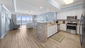A modern kitchen with white cabinets, stainless steel appliances, and a large island. - Direct Beachfront Lazy River Waterslide-Hot tub-Indoor Pool-Walk to restaurants (Orange Beach)