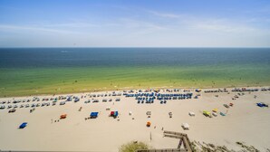 A beach with rows of umbrellas and beach chairs, a clear sky, and the ocean in the background. - Direct Beachfront Lazy River Waterslide-Hot tub-Indoor Pool-Walk to restaurants (Orange Beach)