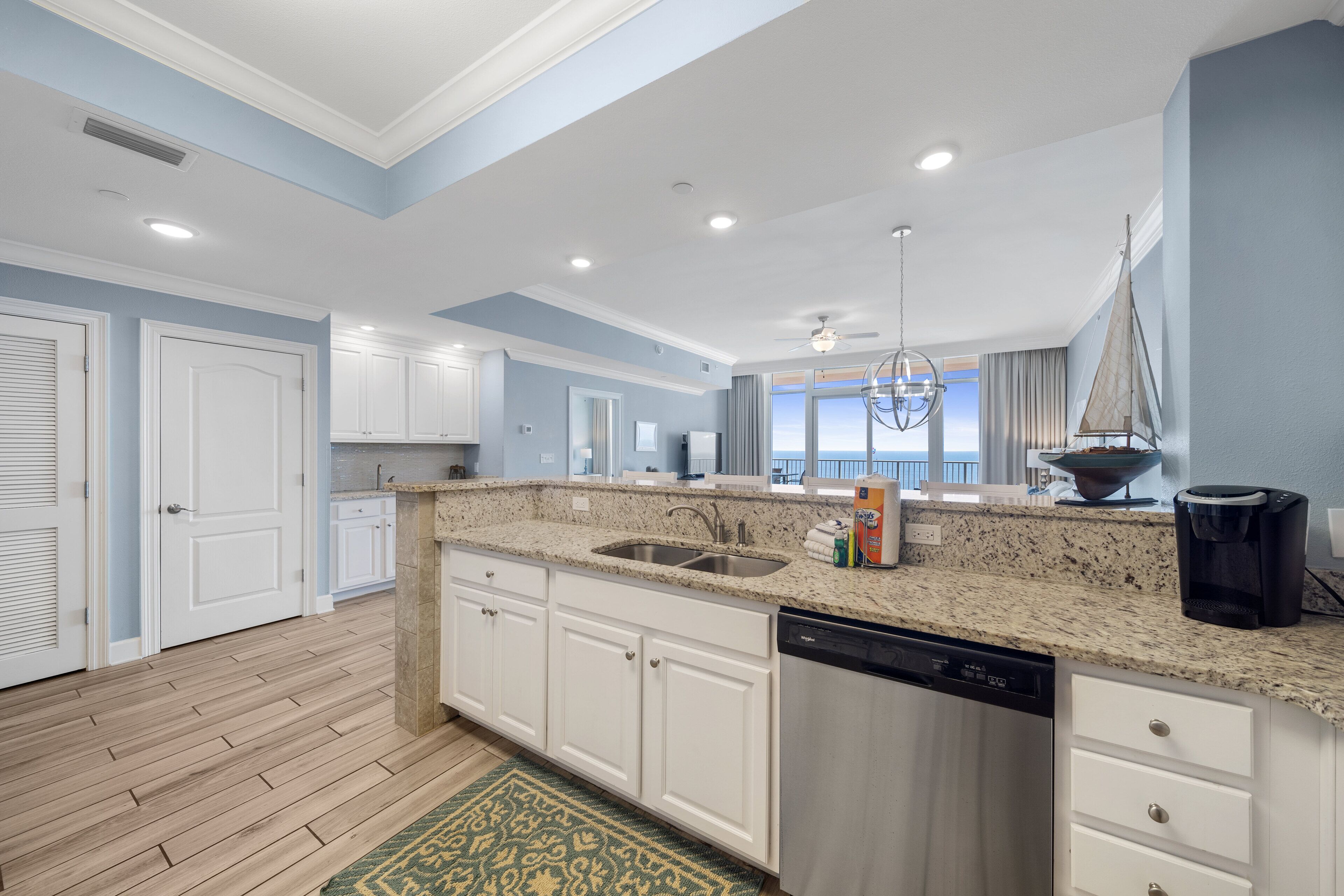 A modern kitchen with white cabinets, granite countertops, and a dishwasher.