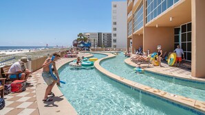 A pool area with a water slide, lounge chairs, and a view of the beach. - Direct Beachfront Lazy River Waterslide-Hot tub-Indoor Pool-Walk to restaurants (Orange Beach)