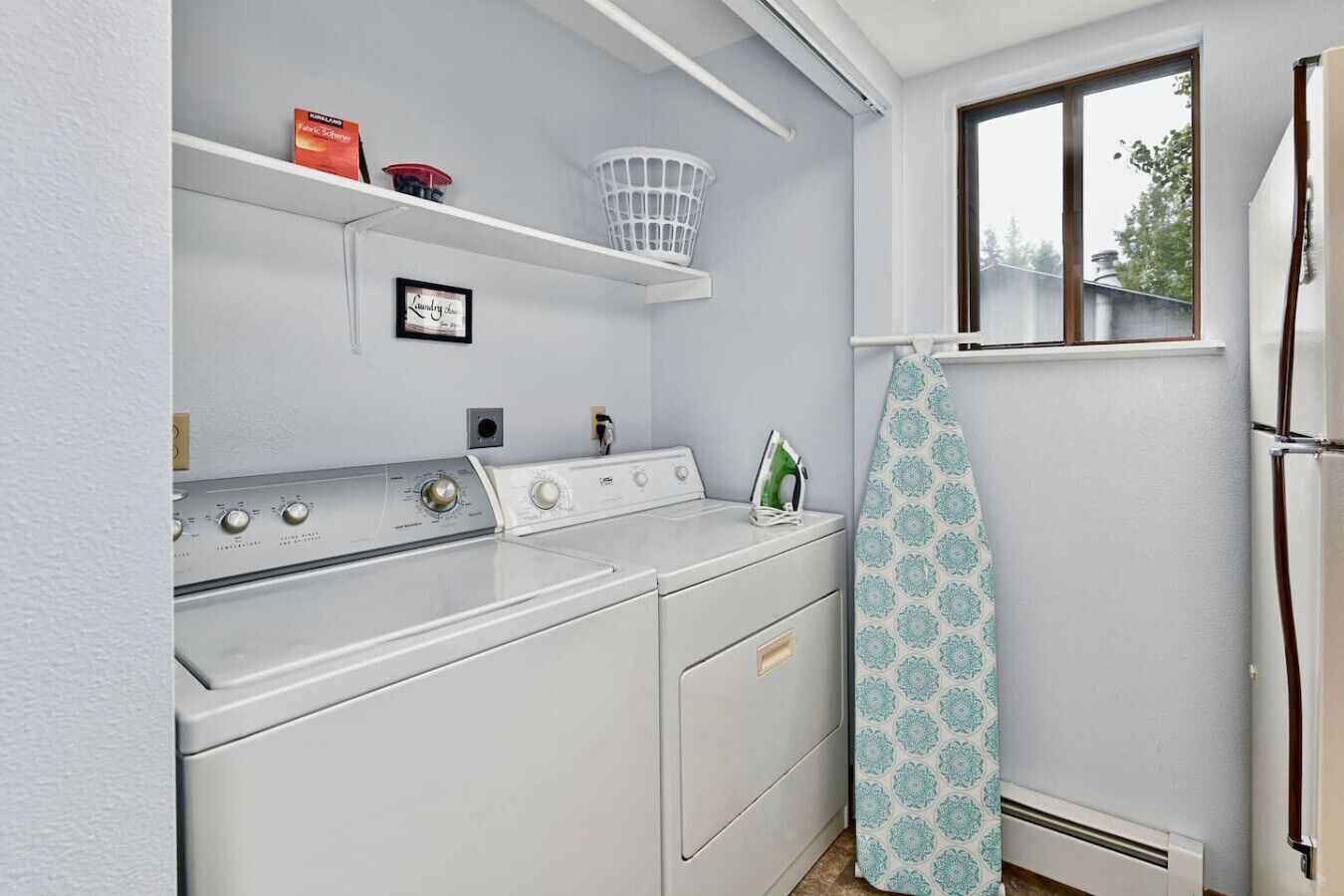 A laundry room with a washing machine, dryer, and ironing board.