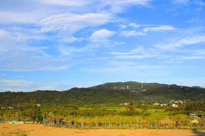 A coastal landscape with a sandy beach, a grassy area, and a hill with several buildings and structures. - Surfspot House (Hengchun)