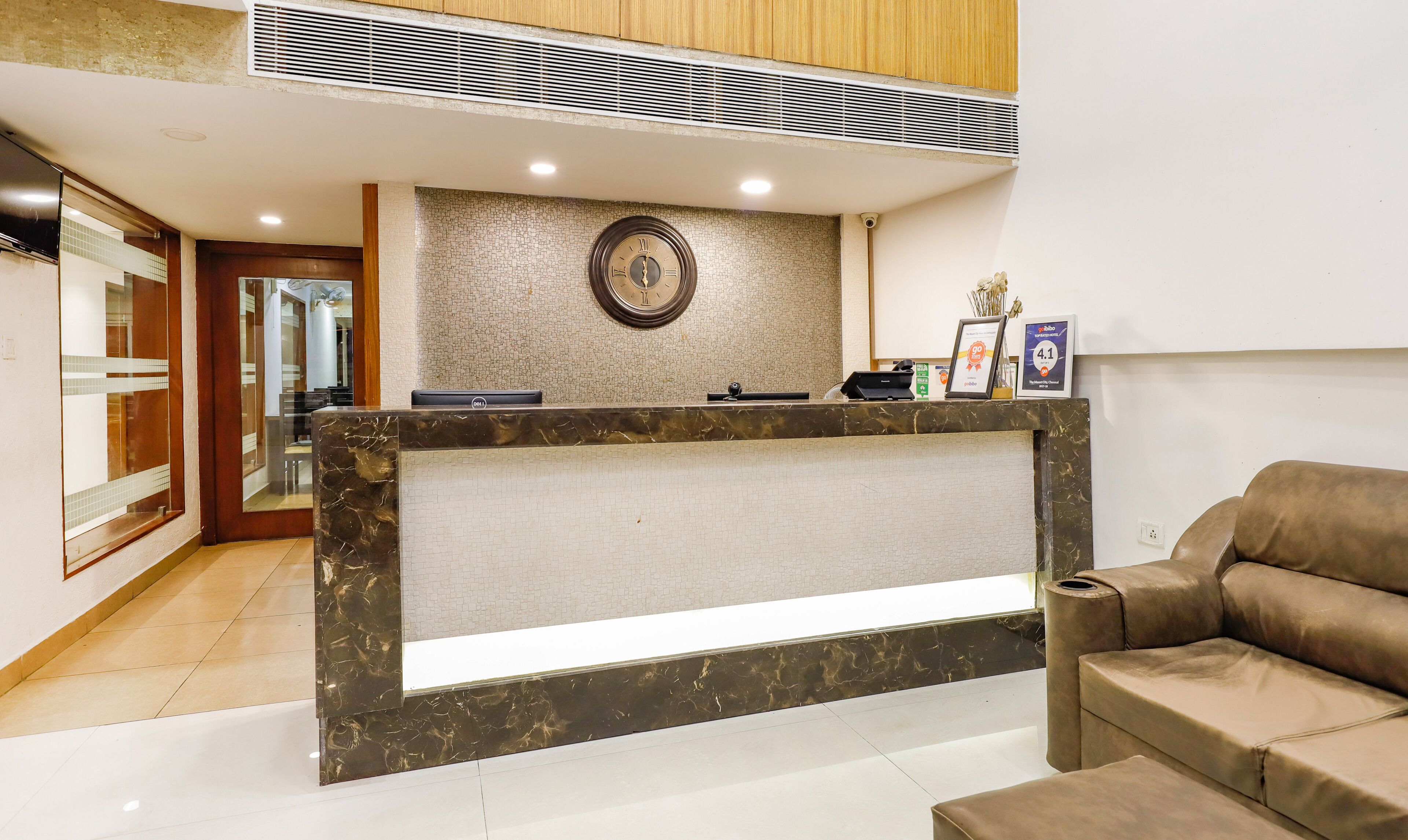 A reception desk with a clock, a framed certificate, and a small plant.