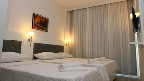 A hotel room with two beds, each with white linens and pillows, a headboard, and a wall-mounted TV. - Liman Boutique Otel (Kemer)