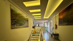 A hotel reception area with a staircase leading to the upper floors, marked with directional signs for rooms, a reception desk, and a fire extinguisher. - Liman Boutique Otel (Kemer)
