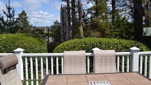 Een terras met een witte reling, een tafel en stoelen.