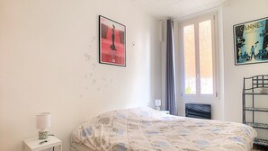 Un dormitorio con una cama, una mesita de noche, una ventana con cortinas y carteles en la pared.