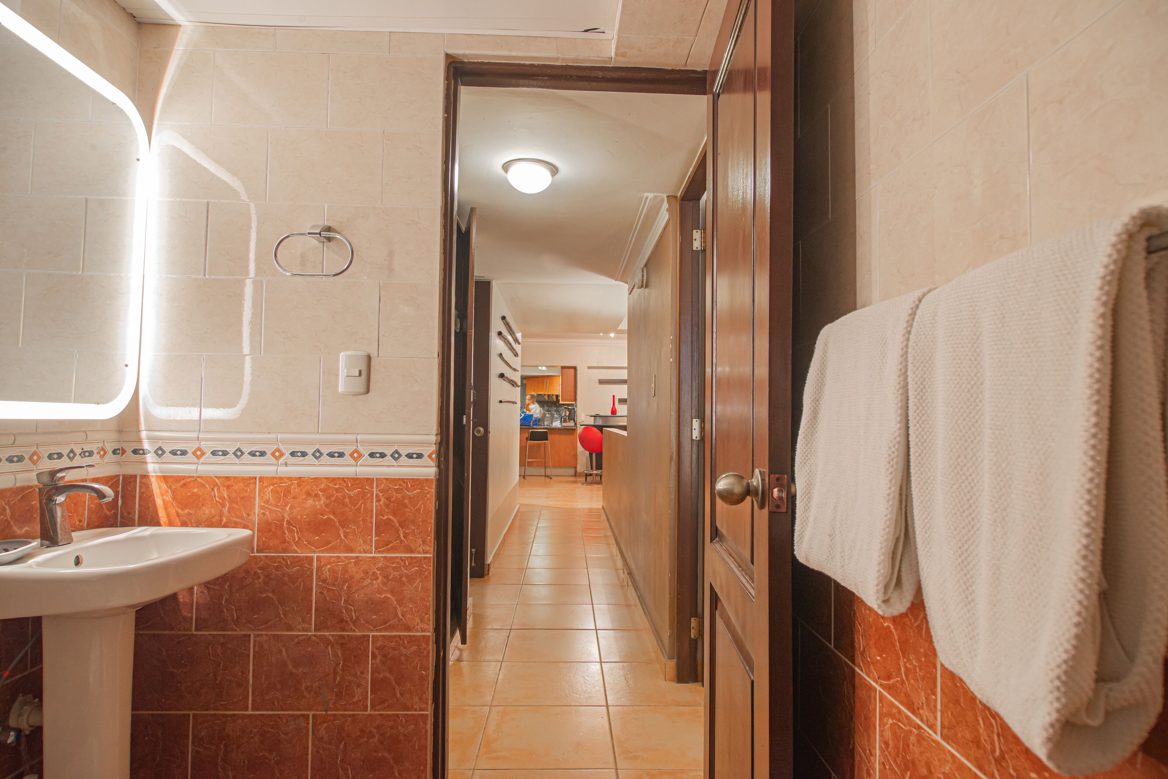 Une salle de bain avec un lavabo, un miroir et une serviette accrochée au mur.