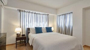 Ein Hotelzimmer mit einem Bett, einem Nachttisch mit Lampe und Vorhängen.