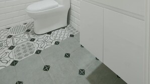 Un baño moderno con inodoro blanco, cabina de ducha de vidrio y lavamanos blanco con espejo sobre él.
