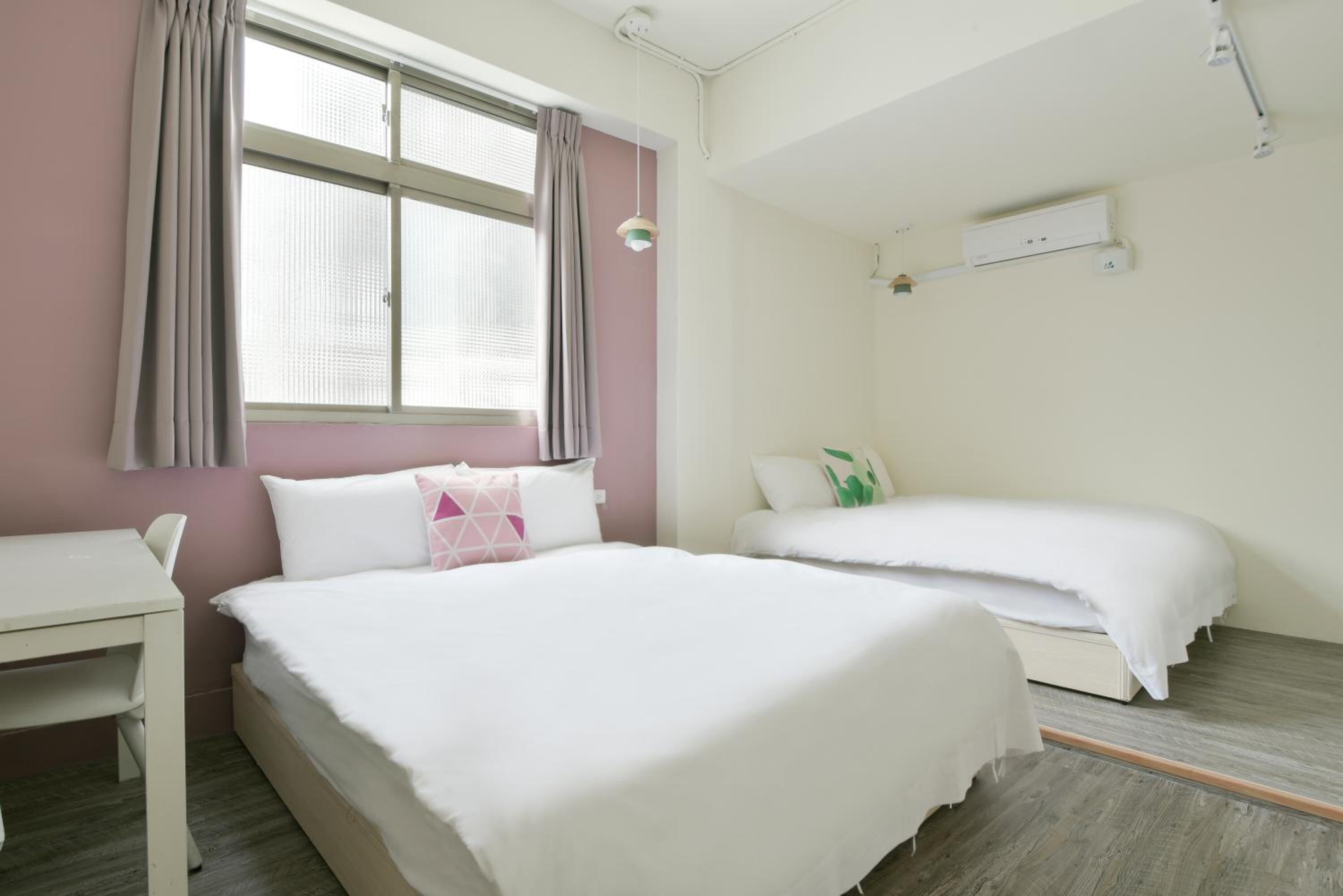 A bedroom with a bed, a desk, and a window with curtains.