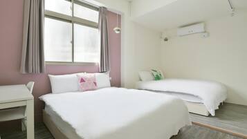 A bedroom with a bed, a desk, and a window with curtains.