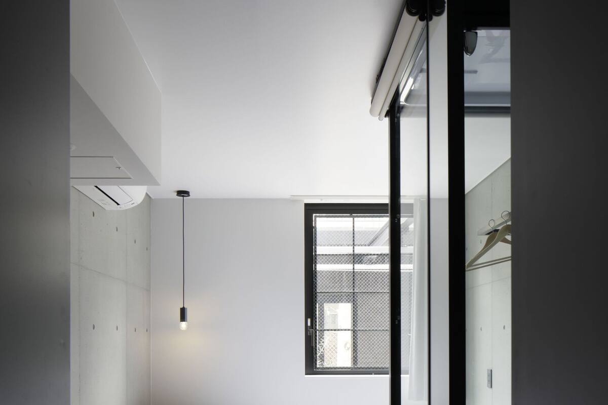 A compact hotel room with a bed, a desk with a chair, a small table, and a window.