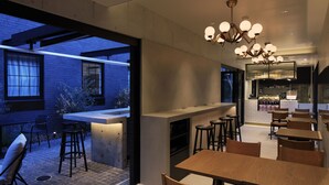 En moderne restaurant med barområde, træborde og stole.