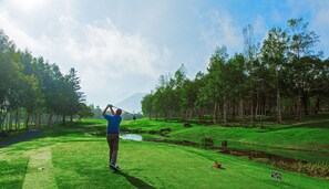 A golf course with a person preparing to swing, surrounded by lush greenery and trees. - Mercure Niseko Resort (Formerly known as Midtown Niseko) (Kutchan)