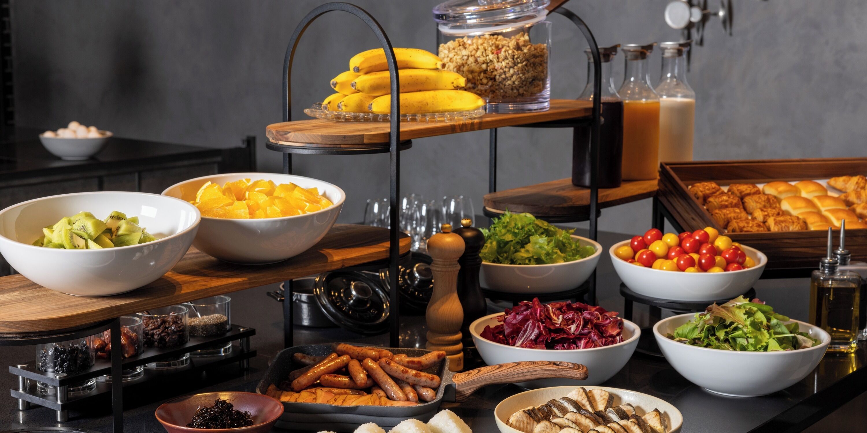 A buffet table with various food items including fruits, vegetables, and meats.