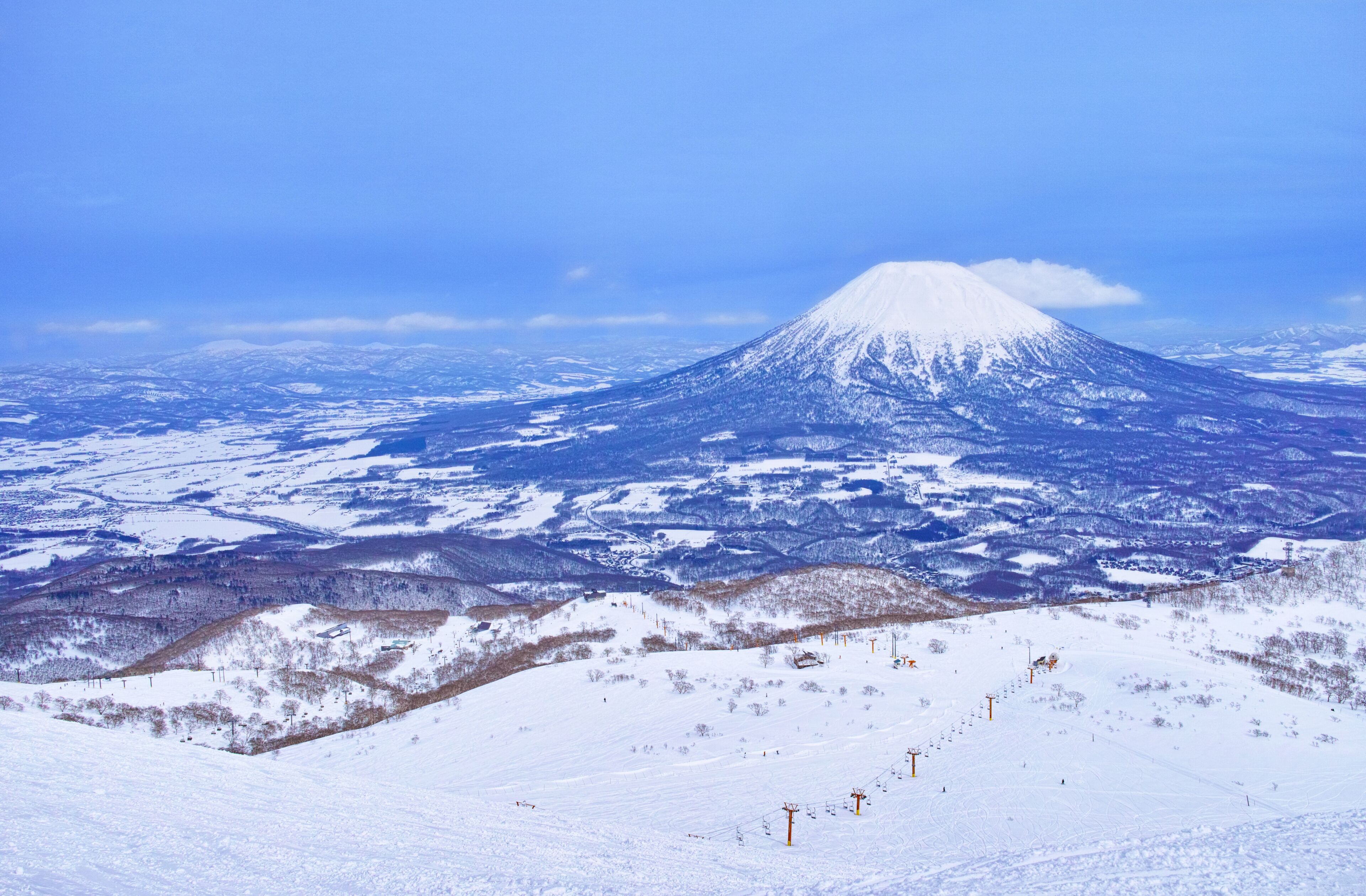 Une montagne enneigée, avec une station de ski au premier plan.