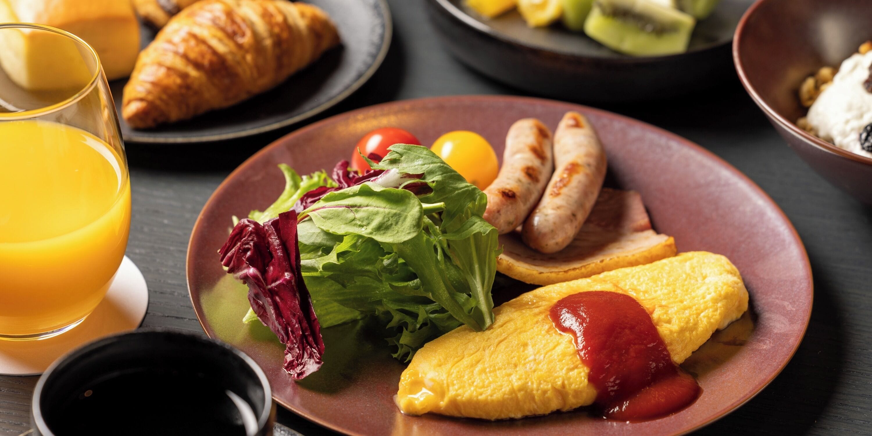 A breakfast plate with eggs, sausages, and salad.