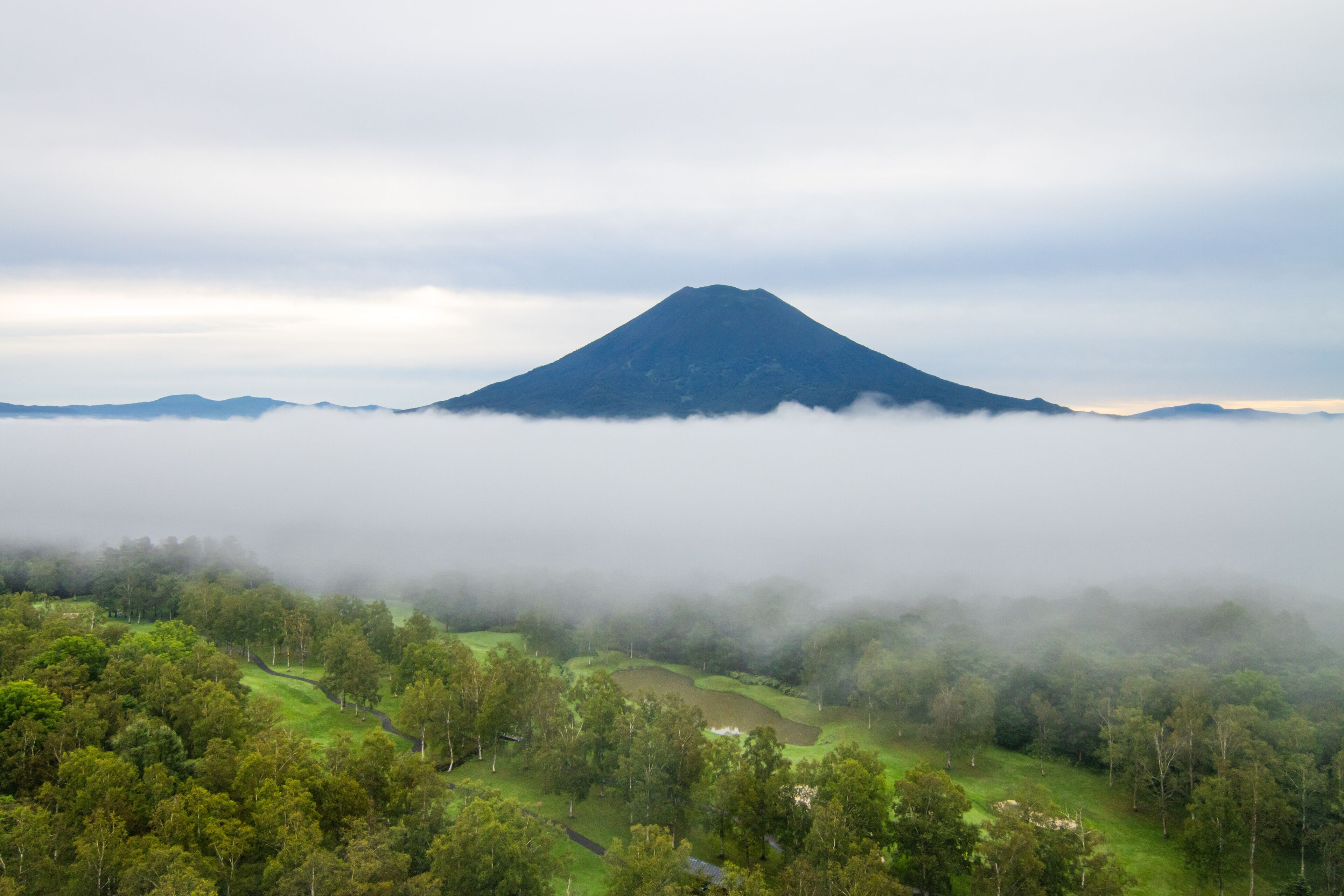 A mountain partially obscured by fog, with a valley below.