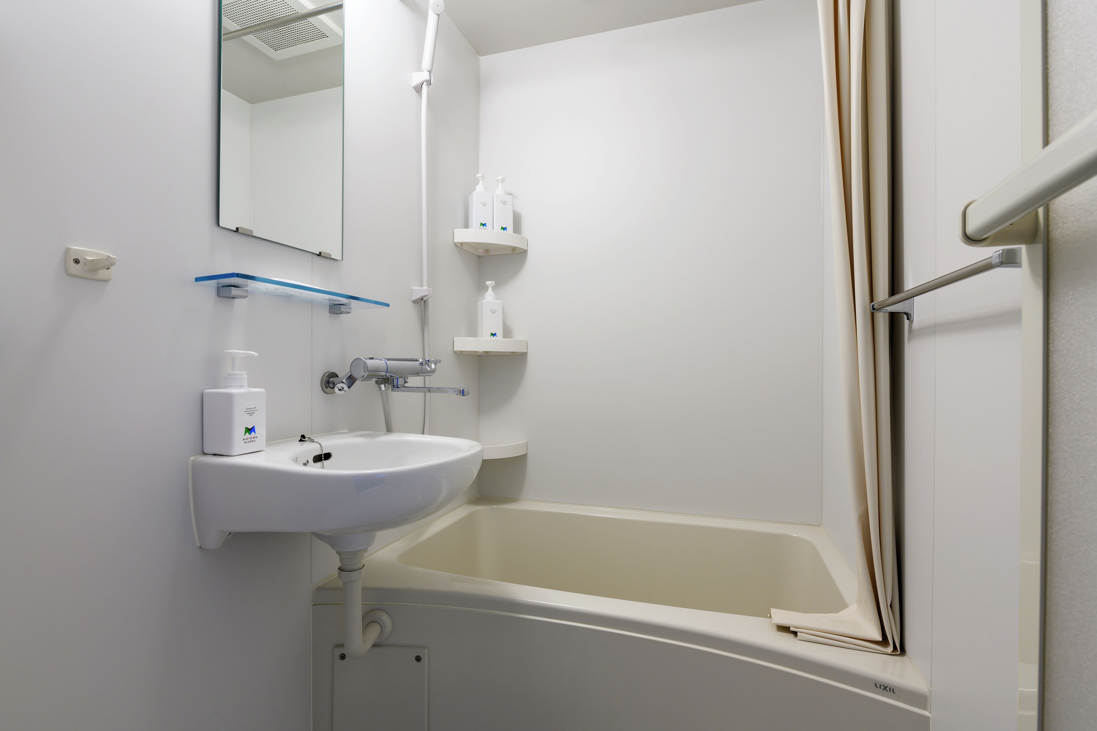 A bathroom with a sink, mirror, and bathtub.