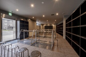 A modern interior with metal furniture, a view through the door, and a row of numbered lockers.