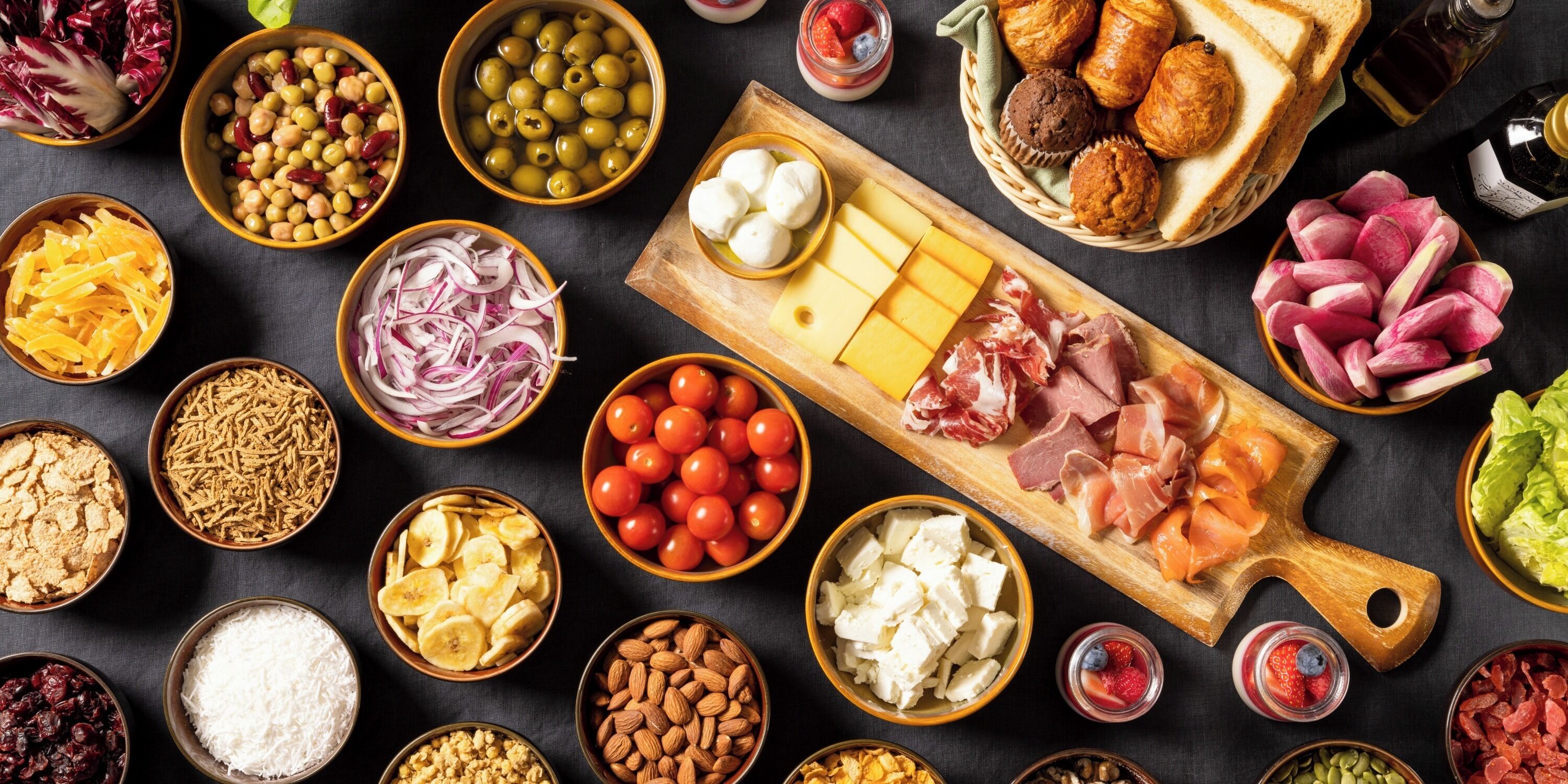 A variety of food items including olives, cheese, cured meats, and fruits arranged on a table.