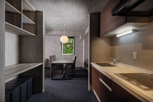 A compact kitchen with a built-in stove, a dining area with a table and chairs, and a window providing a view of greenery.