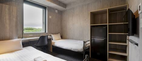 A hotel room with two beds, a desk, a chair, a wardrobe, and a TV.