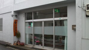 Un edificio con entrada de vidrio, una señal de salida verde y un letrero con caracteres japoneses.
