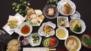 Variedad de platos japoneses, como sushi, sashimi y cuencos de arroz, presentados sobre una mesa.