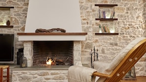 Una chimenea de piedra con un televisor y estanterías arriba.