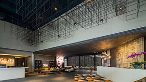 Een ruime lobby met een hoog plafond, een vloer met geometrische patronen en een receptiebalie.