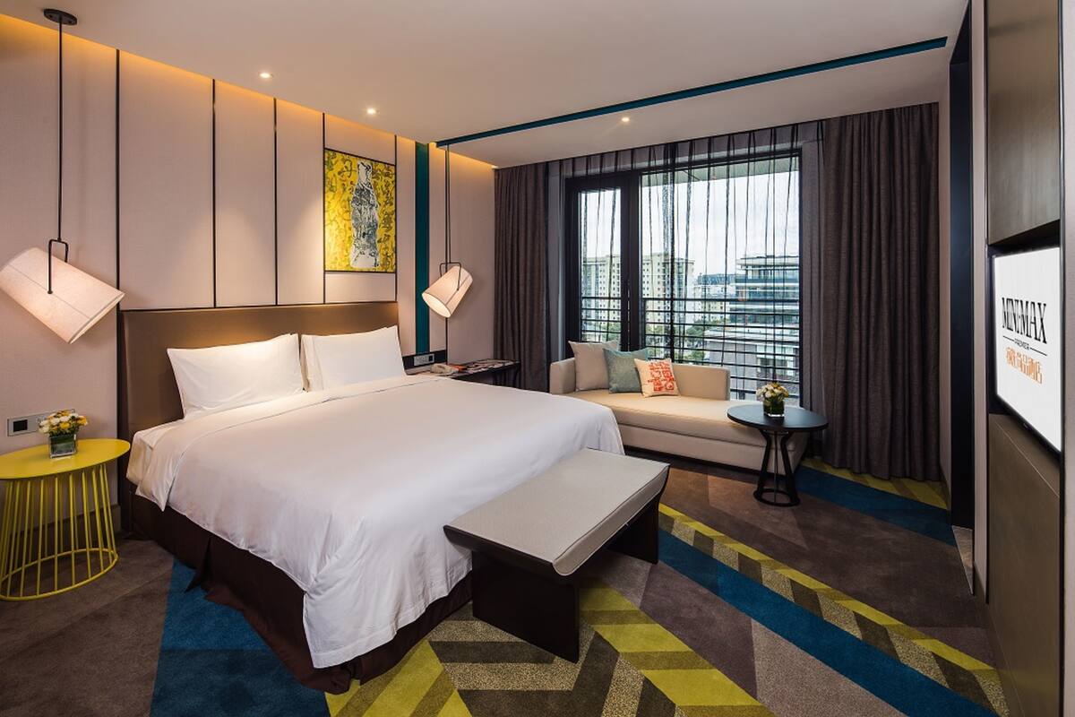 A hotel room with a large bed, a sofa, a small table, and a TV.