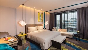 Een moderne hotelkamer met een groot bed, een slaapbank, een eettafel en een klein bijzettafeltje.