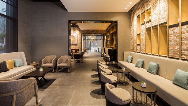 Een moderne loungehoek met banken, fauteuils en ronde tafels.